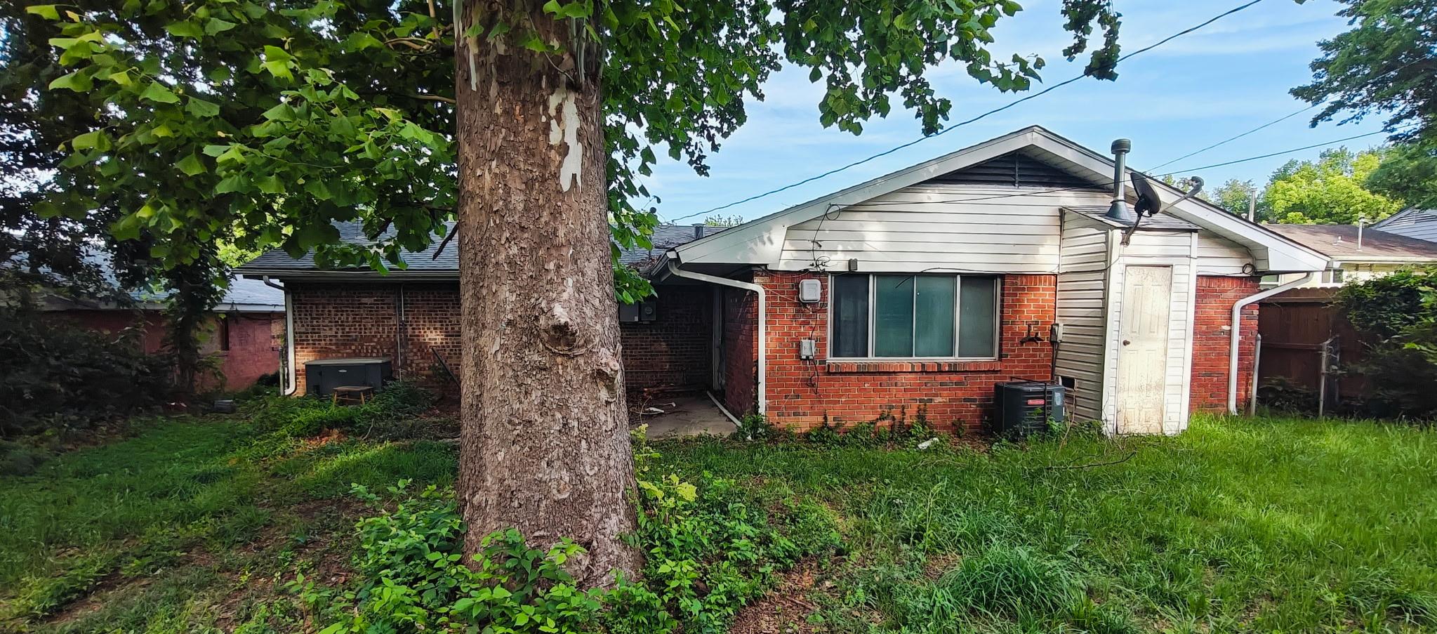 Back exterior with large tree and brick facade