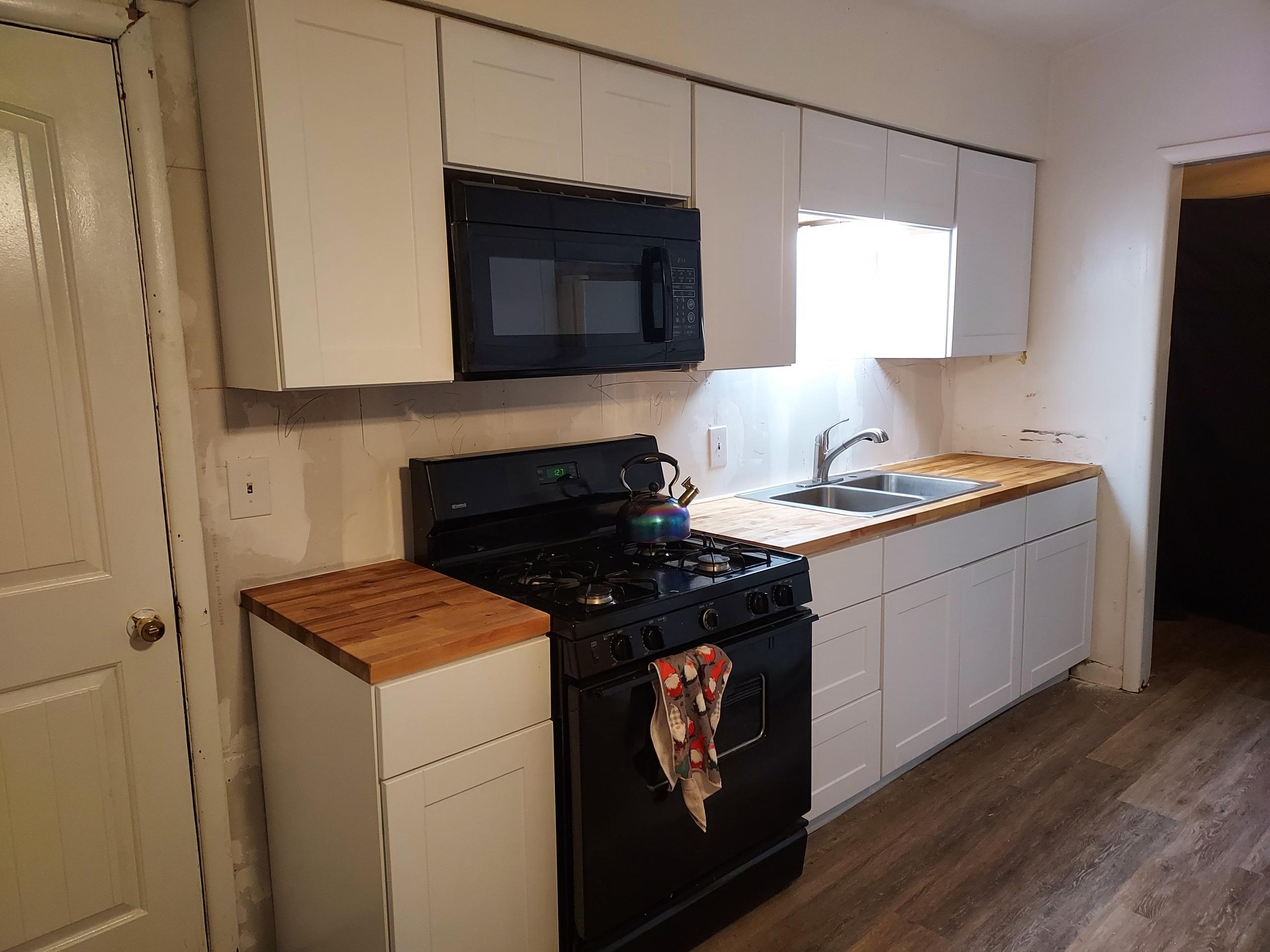 Kitchen with butcher block counters and black appliances