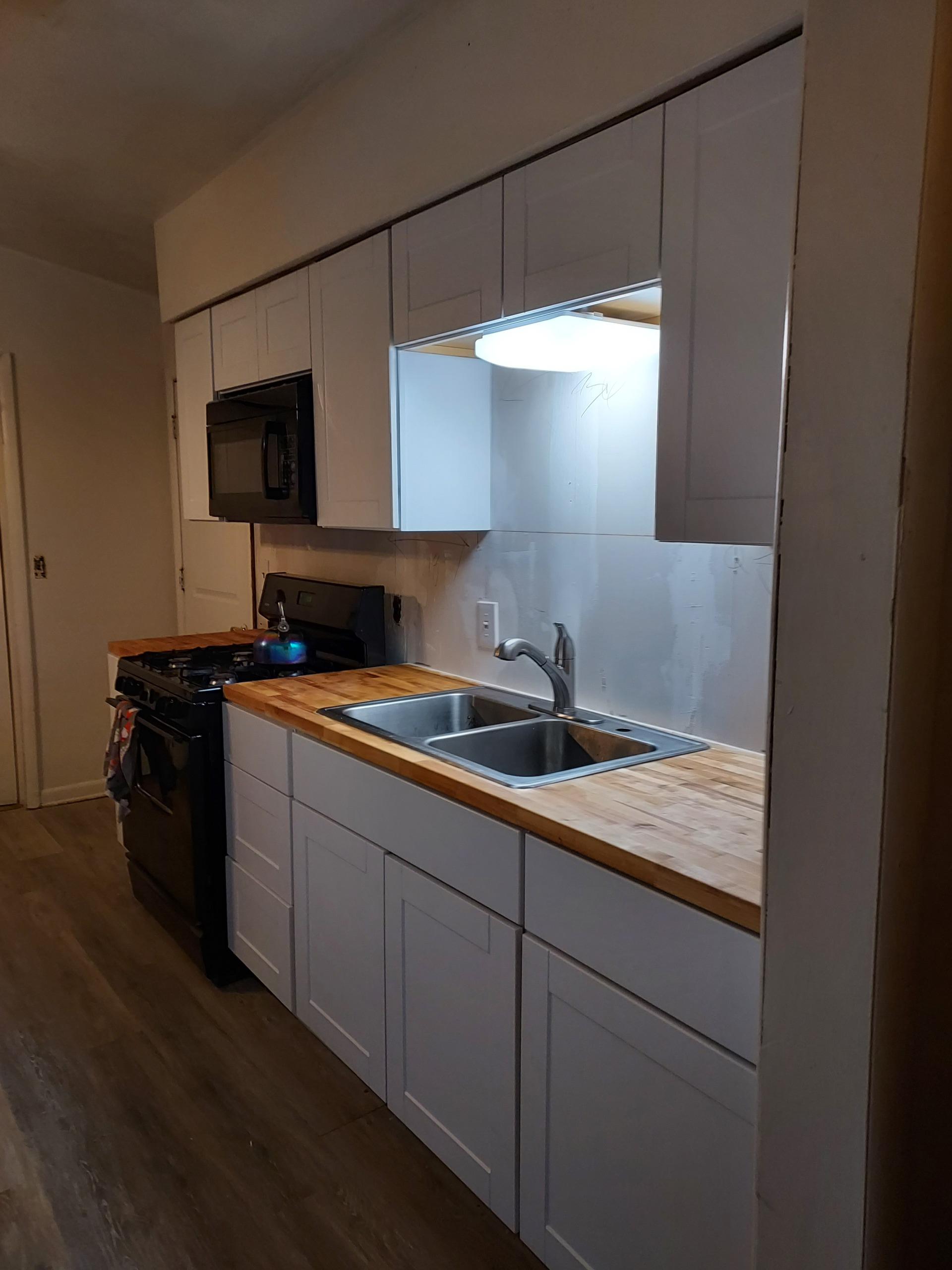 Kitchen with butcher block counters and white cabinets